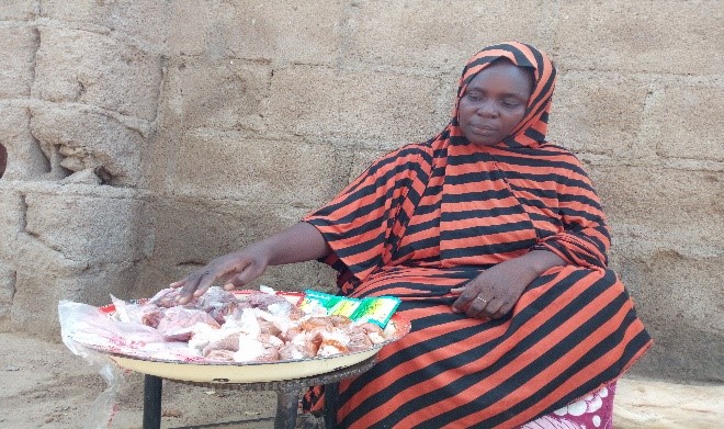 A participant sits at a table with a large plate filled with raw meat cuts.