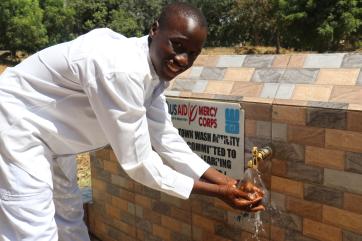 Young person at outdoor water pump station in nigeria