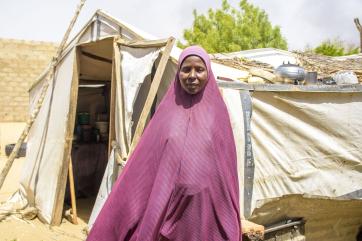 A person in front of their old makeshift shelter.