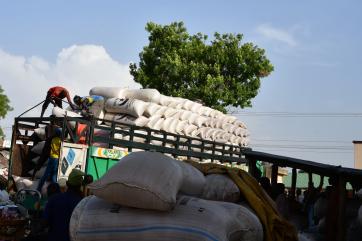 People loading a truck with grains.