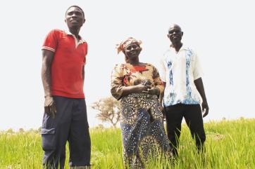 Three farmers standing in a field.