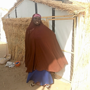 A person posing in front of a shelter.