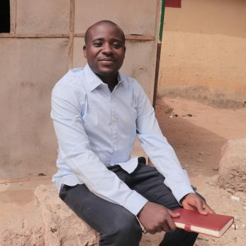 A person holding a bible sitting on a small step.