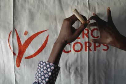 Hands writing over mercy corps logo