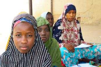 Three young people and their educator look into the camera during a lesson in nigeria.
