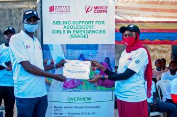 A mercy corps team member presents a certificate of recognition to a coordinators of the ssage program safe spaces in maiduguri, borno state.