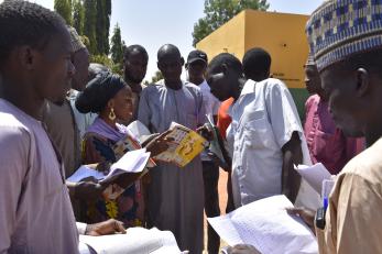 Salome samuel checking the accounts of the vslas in kwami town.