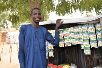 Adam abba, standing in front of the small grocery business he started.