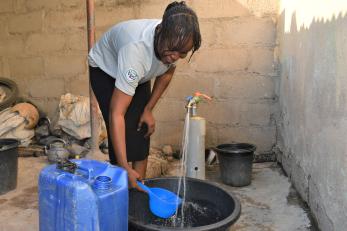 A person using a water spigot.