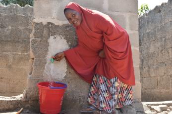 A person filling a bucket with water.