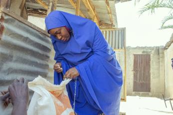 A person opening a bag of chicken feed.