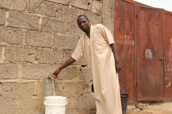 A person filling a bucket with water.