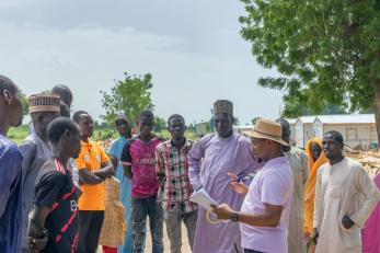 Mercy corps staff mohammed umar addressing a crowd before participant verification exercise commences.