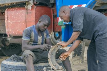 Two nigerian men holding a mechanical part