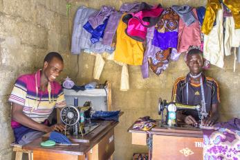 Two people sitting at sewing machines.