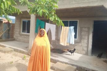 Gwoza permanent shelter participant, aboko tijjani standing happily in front of her newly constructed shelter.