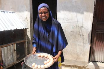 A person smiles while carrying chicken eggs. 