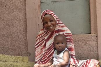 A person smiling while holding a baby.