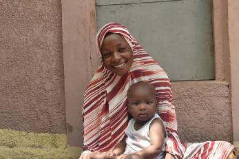 A person smiling while holding a baby. 