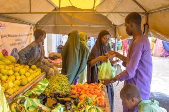 A vendor buying produce from a vendor.