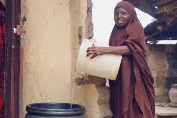 A person pouring water from a bucket.