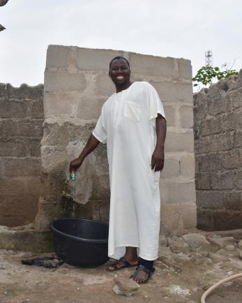 A person in their house using the water-tap connected to the water facility.