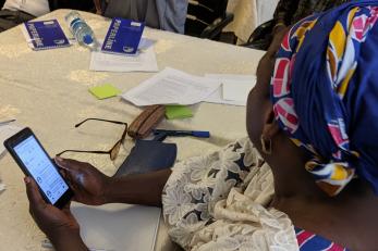 A particpant holds a mobile phone and listens to a lesson on using the YAFE app.