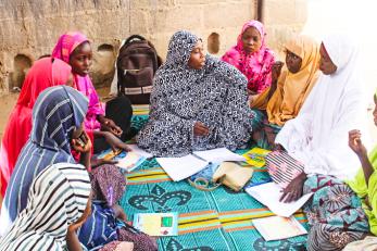A mentor leads a lesson for young people while they sit in a group in Nigeria.