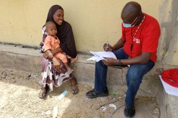 A Mercy Corps representative completing paperwork with a participant.  