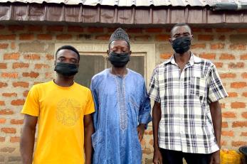 Three people standing together wearing face masks.