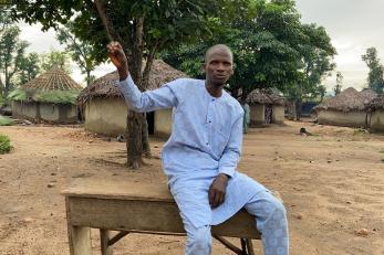 A person sitting on a bench and speaking.