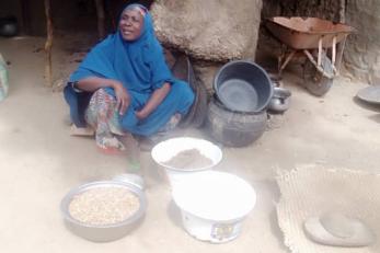 Nigerian woman sits behind examples of her ground nut crop.