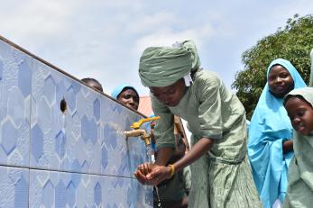 A young person using a water spigot.