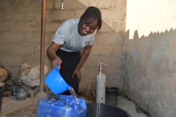 A person pouring water into a vessel.