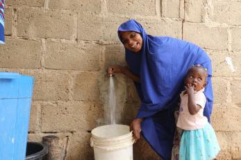 A person filling a bucket with water.