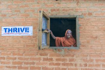 Nigerian woman holding the window open of her home