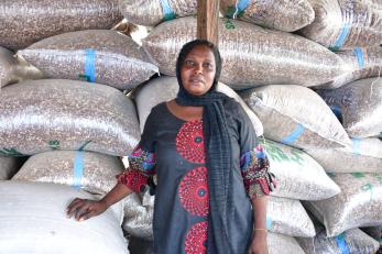 A person standing with many large bags of grain.