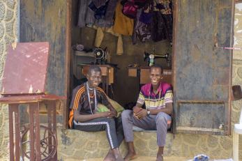 Two people sitting in front of their workshop.