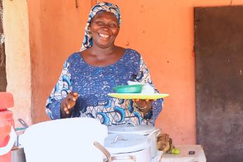 A vendor preparing a plat of food for a customer.