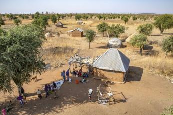 An aerial view of farmer and herder community members gathering.