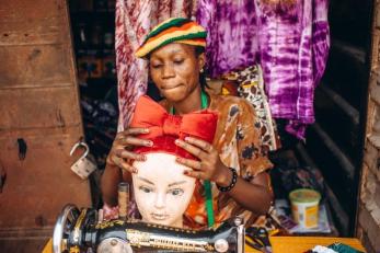 Oluwayemisi fitting a scarf she designed and made onto a mannequin.