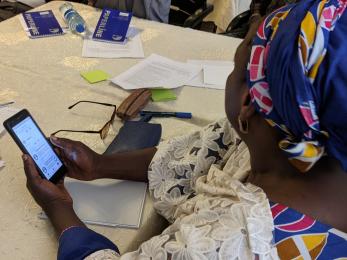 A particpant holds a mobile phone and listens to a lesson on using the yafe app.