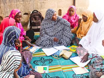 A mentor leads a lesson for young people while they sit in a group in nigeria.