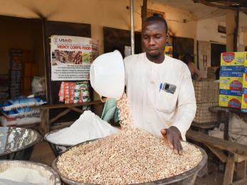 A person pouring dry goods into a bowl. 