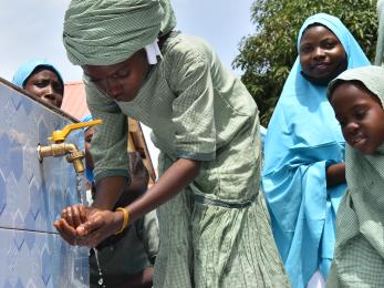 A young person using a water spigot.