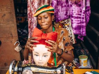 Oluwayemisi fitting a scarf she designed and made onto a mannequin.